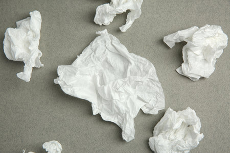Used paper tissue on gray background, flat lay