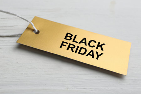 Blank golden tag on white wooden background, closeup. black friday conceptの写真素材