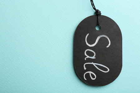 Top view of tag with word SALE on turquoise background, space for text. black friday concept
