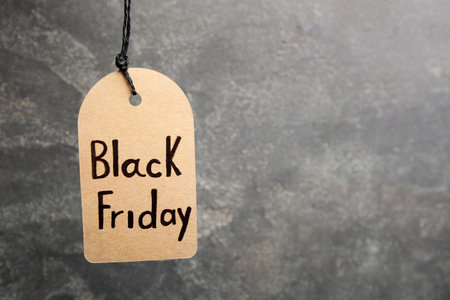 Tag with words BLACK FRIDAY hanging on gray background. Space for text