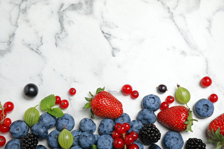 Mix of fresh berries on white marble table, flat lay. Space for text