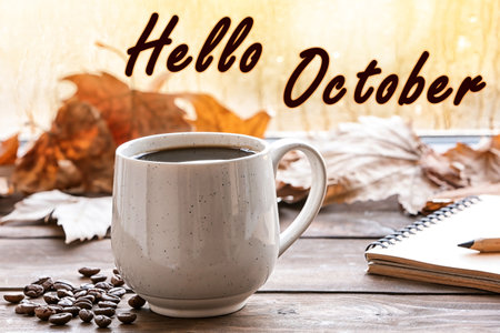 Hello October card. Cup of hot drink and autumn leaves on wooden table