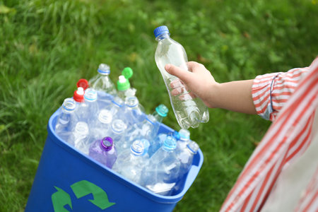 Woman throwing used bottle into trash bin outdoors, closeup. plastic recyclingの写真素材