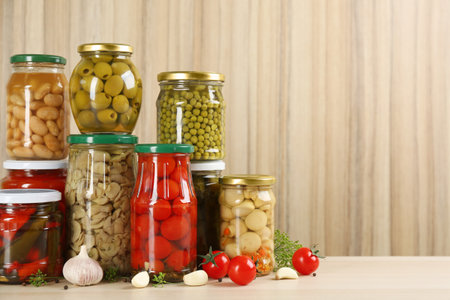 Jars of pickled vegetables on wooden table. Space for textの写真素材