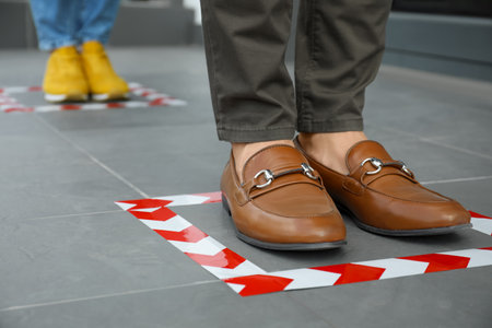 People standing on taped floor markings for social distance, closeup.  pandemicの写真素材