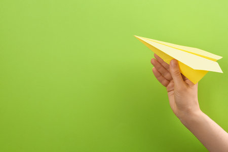 Woman holding paper plane on green background, closeup. Space for textの写真素材