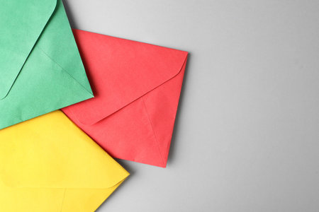 Colorful paper envelopes on light gray background, top view. Space for text