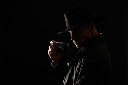 Old fashioned detective with camera on dark background. Space for textの写真素材