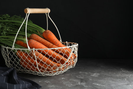 Basket with raw carrots on gray table. Space for textの写真素材