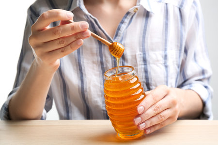 Woman with jar of honey at wooden table, closeupの写真素材