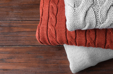 Stack of folded warm sweaters on wooden background, closeupの写真素材