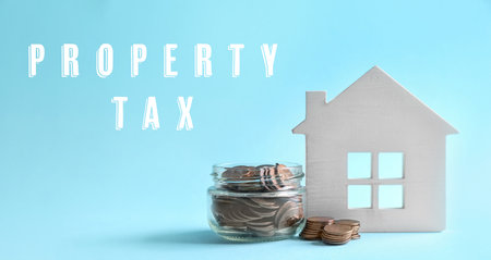 Text Property Tax near jar full of coins and house model on light blue background. banner designの写真素材
