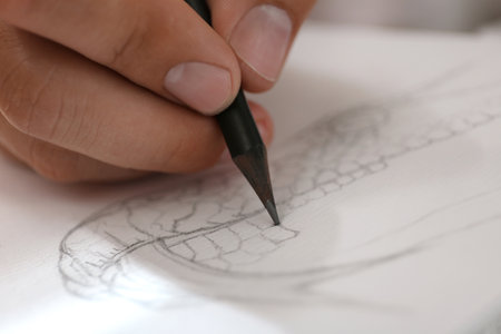 Man drawing snake with pencil in notepad, closeup