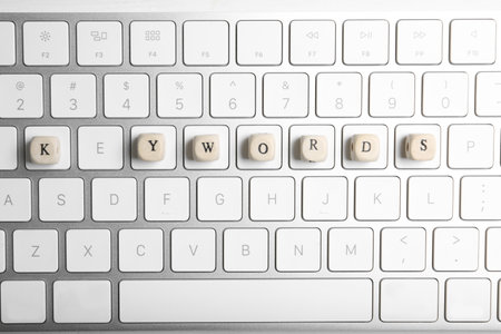 Beads with word KEYWORDS on keyboard, flat lay