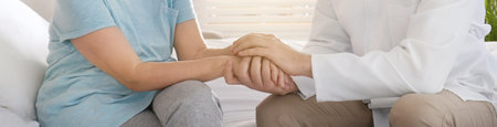 Doctor and senior patient holding hands in hospital, closeup. banner designの写真素材