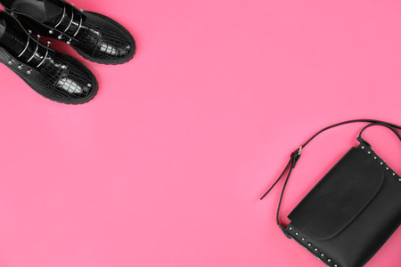 Pair of stylish ankle boots and bag on pink background, flat lay. Space for textの写真素材