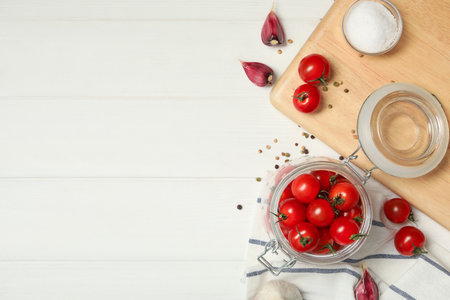 Pickling jar with fresh ripe cherry tomatoes and spices on white wooden table, flat lay. Space for textの写真素材