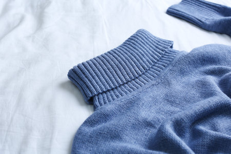 Blue warm sweater on white crumpled fabric, closeupの写真素材