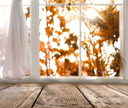 Empty wooden table near window on sunny autumn dayの写真素材