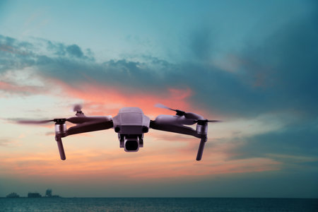 Modern drone flying over the sea at sunset. Aerial survey