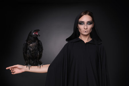 Mysterious witch with raven on dark background