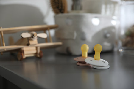 Pacifiers on gray table in child room, space for text