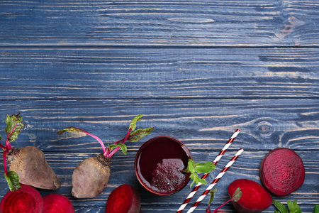 Freshly made beet juice on blue wooden table, flat lay. Space for text