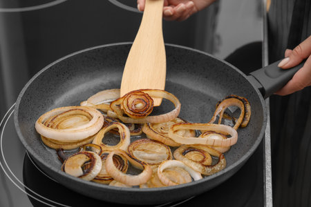 Woman cooking onion rings in frying pan on stove, closeupの写真素材