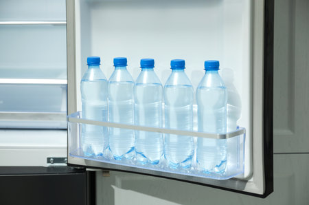 Many bottles with fresh water in fridge door binの写真素材