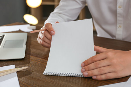 Man with pencil and notepad at wooden table, closeupの写真素材