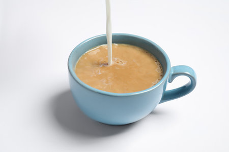 Pouring milk into cup of coffee on white backgroundの写真素材