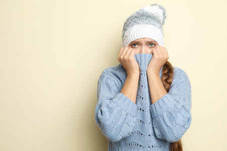 Young woman wearing hat suffering from fever on light background, space for text. Cold symptomsの写真素材