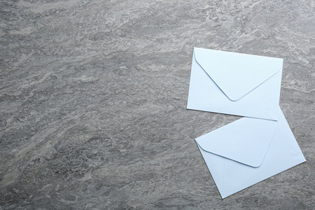 White paper envelopes on gray background, flat lay. Space for text
