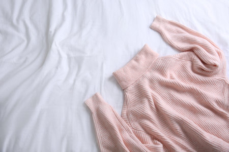 Pink warm sweater on white crumpled fabric, top view. Space for textの写真素材