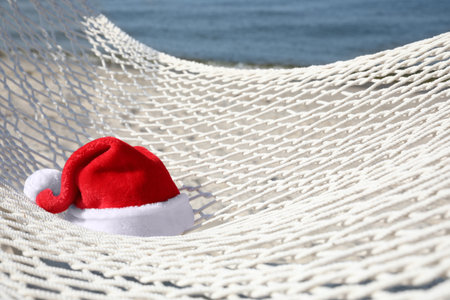 Rope hammock with Santa's hat on beach, closeup. christmas holidays
