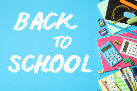 Text Back To School and different stationery on blue background, flat lay