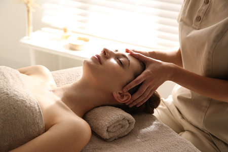 Young woman receiving head massage in spa salonの写真素材