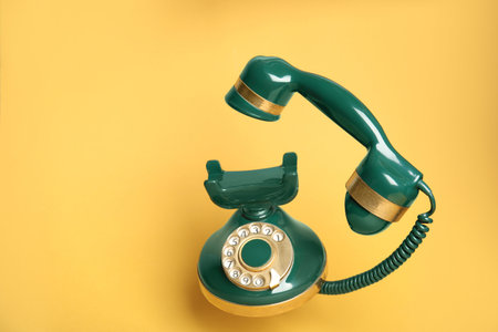 Green vintage corded phone on yellow backgroundの写真素材