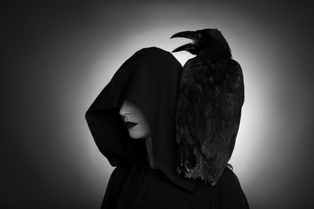 Mysterious witch with raven on dark background. black and white effectの写真素材