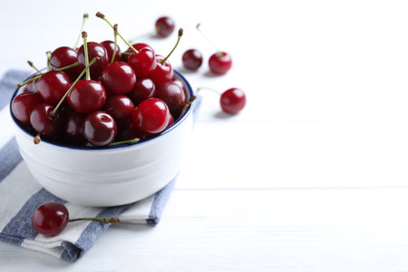 Sweet juicy cherries on white wooden table. Space for text