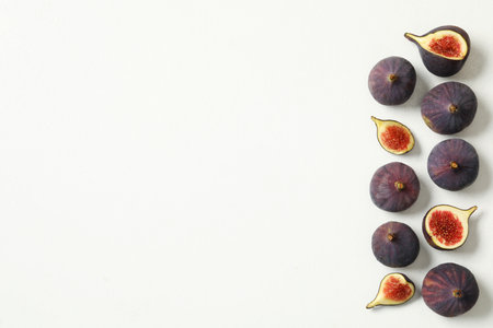 Whole and cut tasty fresh figs on white table, flat lay. Space for textの写真素材