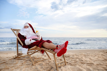 Santa Claus with cocktail relaxing on the beach, space for text. christmas holidaysの写真素材