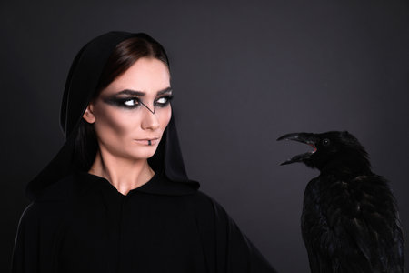 Mysterious witch with raven on black backgroundの写真素材
