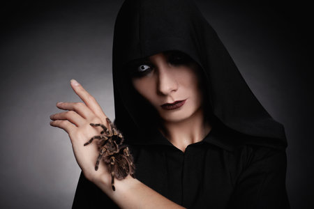 Mysterious witch with spooky spider on dark backgroundの写真素材