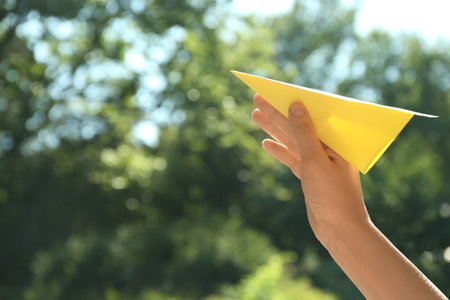 Woman holding paper plane outdoors, closeup. Space for textの写真素材