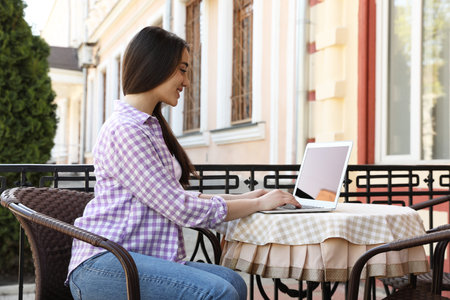 Young woman working on laptop at outdoor cafeの写真素材