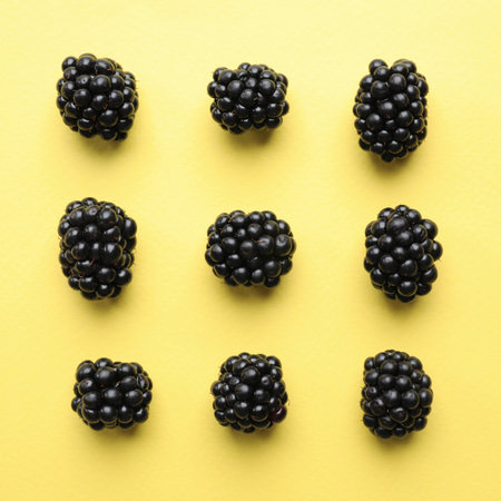 Tasty ripe blackberries on yellow background, flat layの写真素材