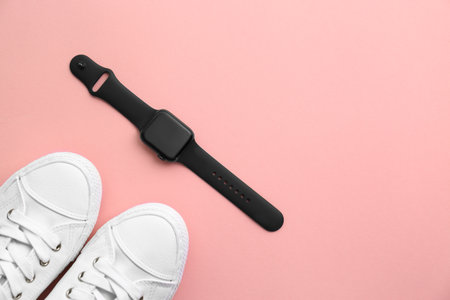 Stylish smart watch and sneakers on pink background, flat lay. Space for text