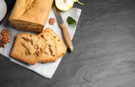 Flat lay composition with pear bread on black slate table, space for text. homemade cake