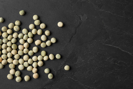 Raw dry peas and space for text on black background, flat lay. vegetable seeds